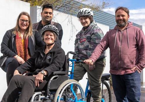 Brite Supported Team members on a blue Brike, surrounded by team members smiling.