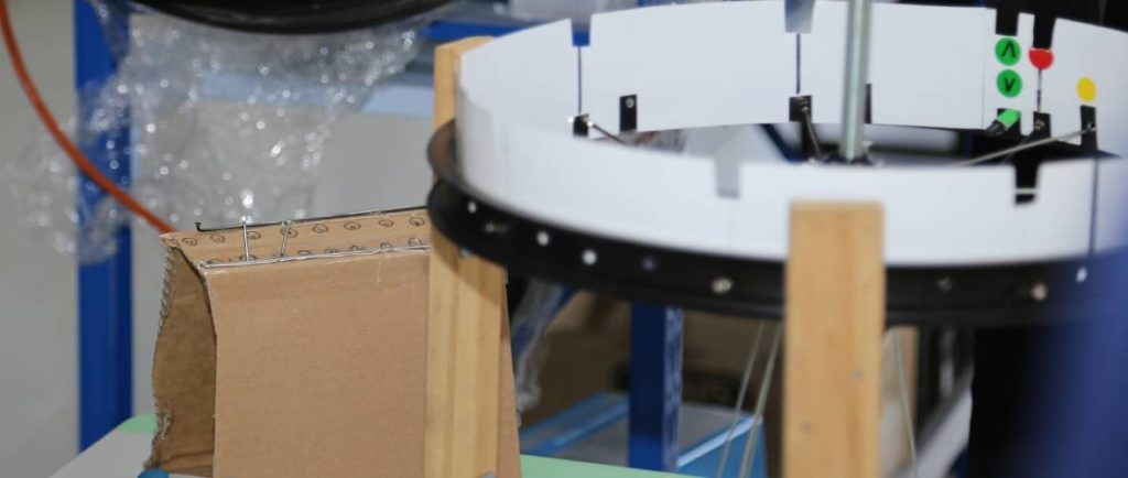 A cardboard box template for sorting spokes sits next to a Brike wheel as it is being built.