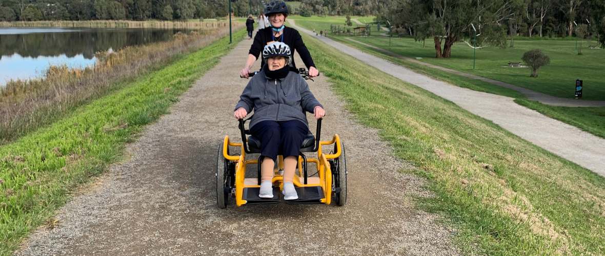 Photo shows an Allity staff member and resident taking a spin on the Brike.