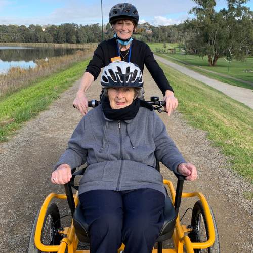 Photo shows an Allity staff member and resident taking a spin on the Brike.