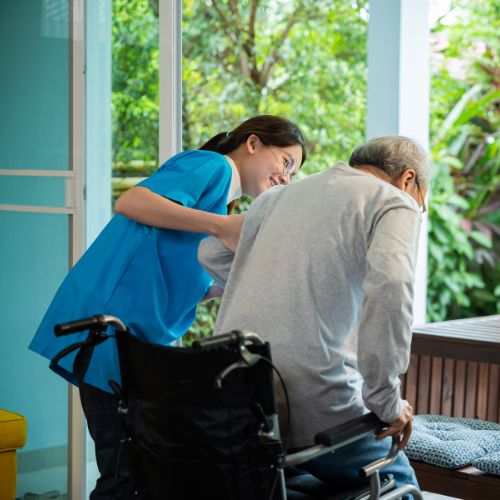 Student helping an elderly man out of his wheelchair